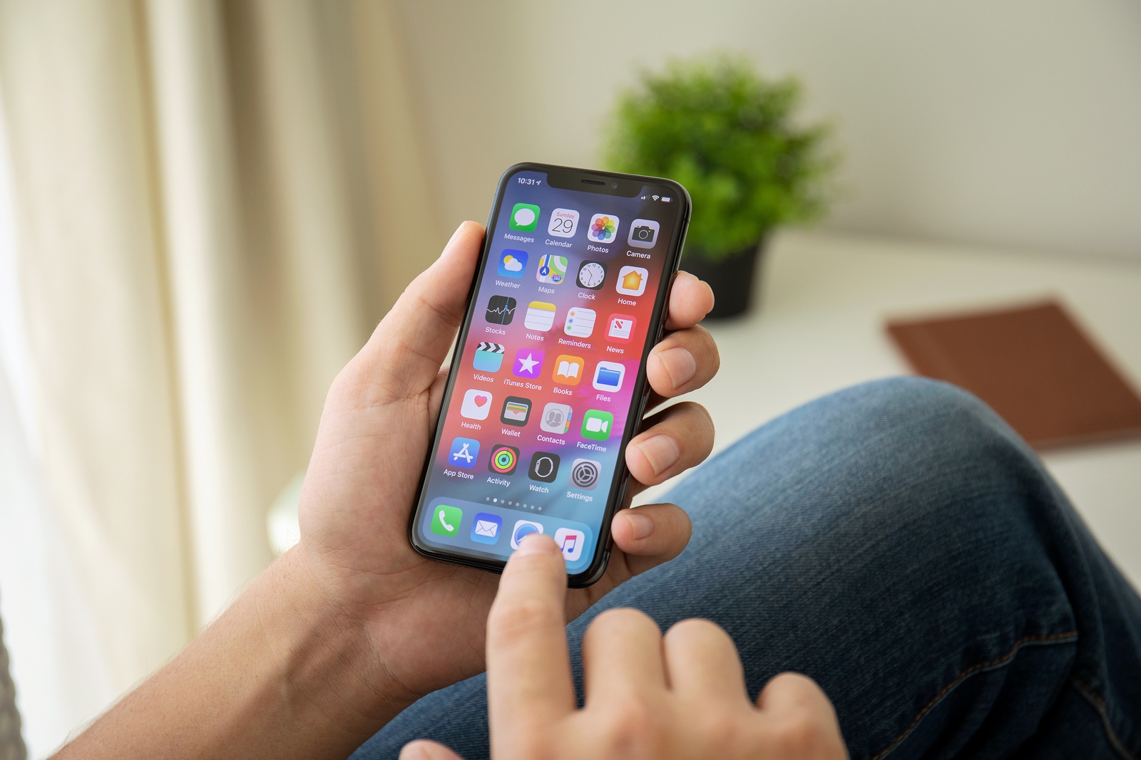 Alushta, Russia - July 29, 2018: Man hand holding iPhone X with home screen IOS. iPhone 10 was created and developed by the Apple inc.