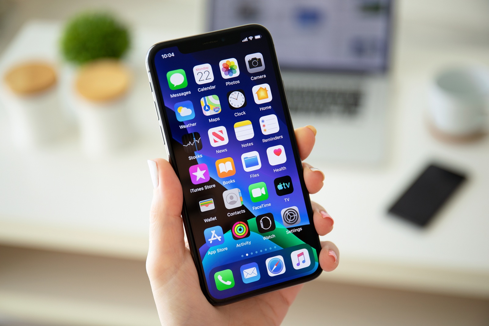 Anapa, Russia - July 22, 2019: Woman hand holding iPhone X with home screen IOS 13. iPhone was created and developed by the Apple inc.