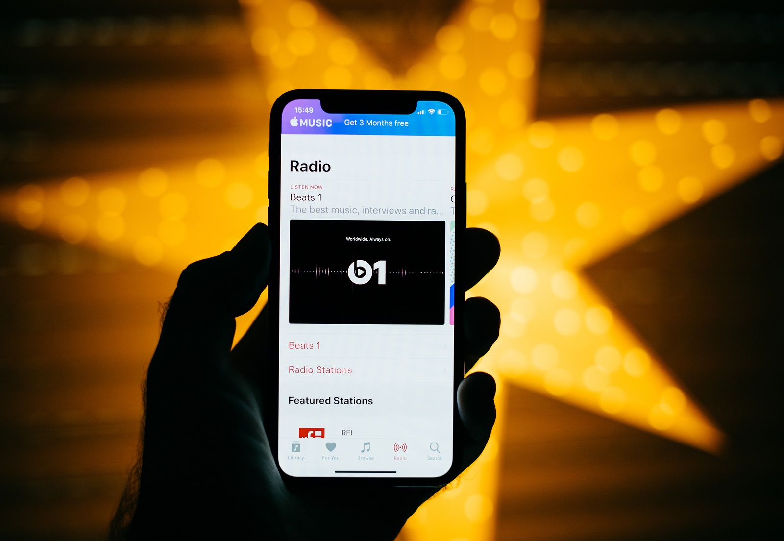 PARIS FRANCE - NOV 10 2017: Man holding the new Apple iPhone X 10 Display with yellow star bokeh background featuring Radio music in the iTunes with Beats 1