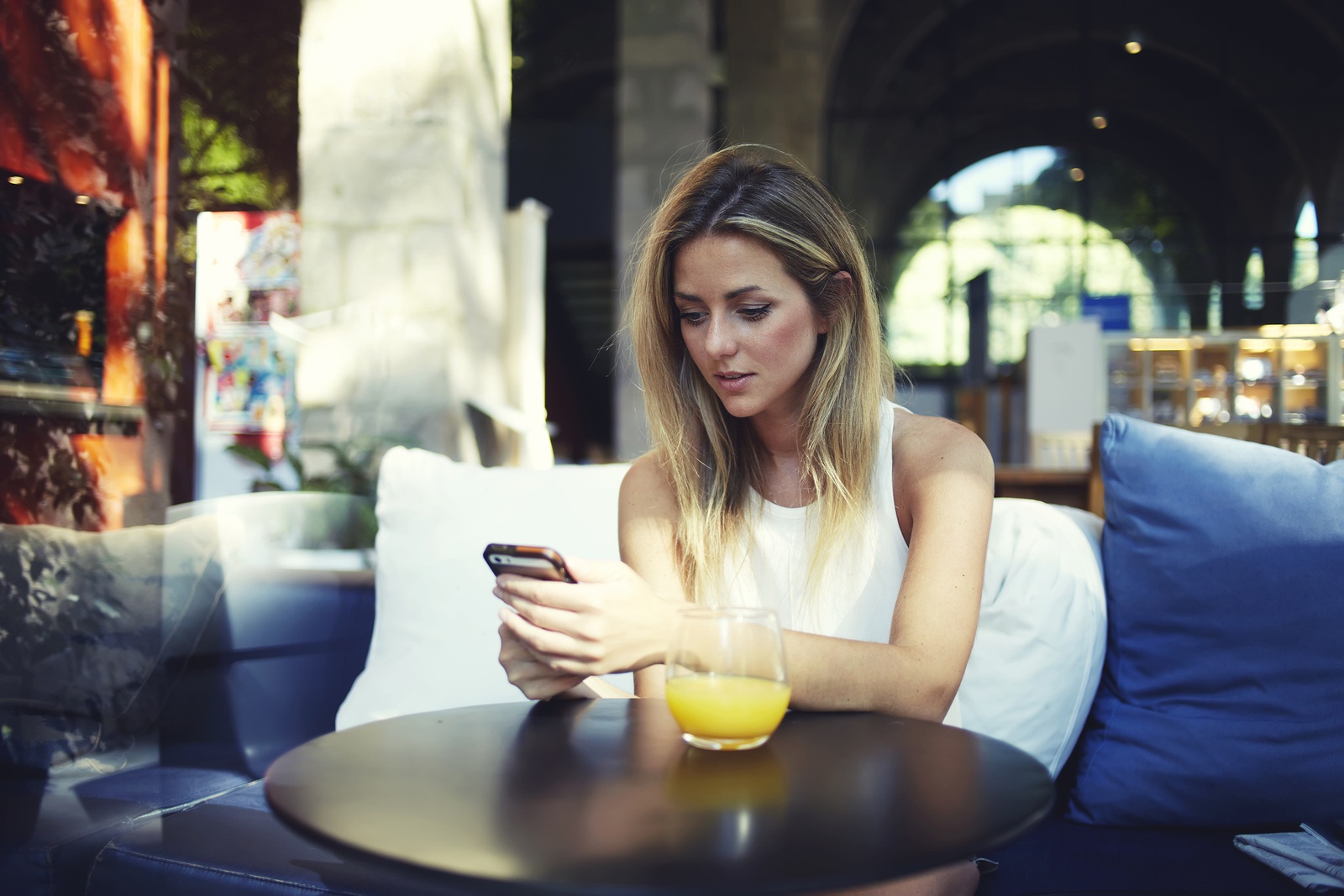 Beautiful young hipster girl using cell telephone while enjoying her free time in expensive cafe