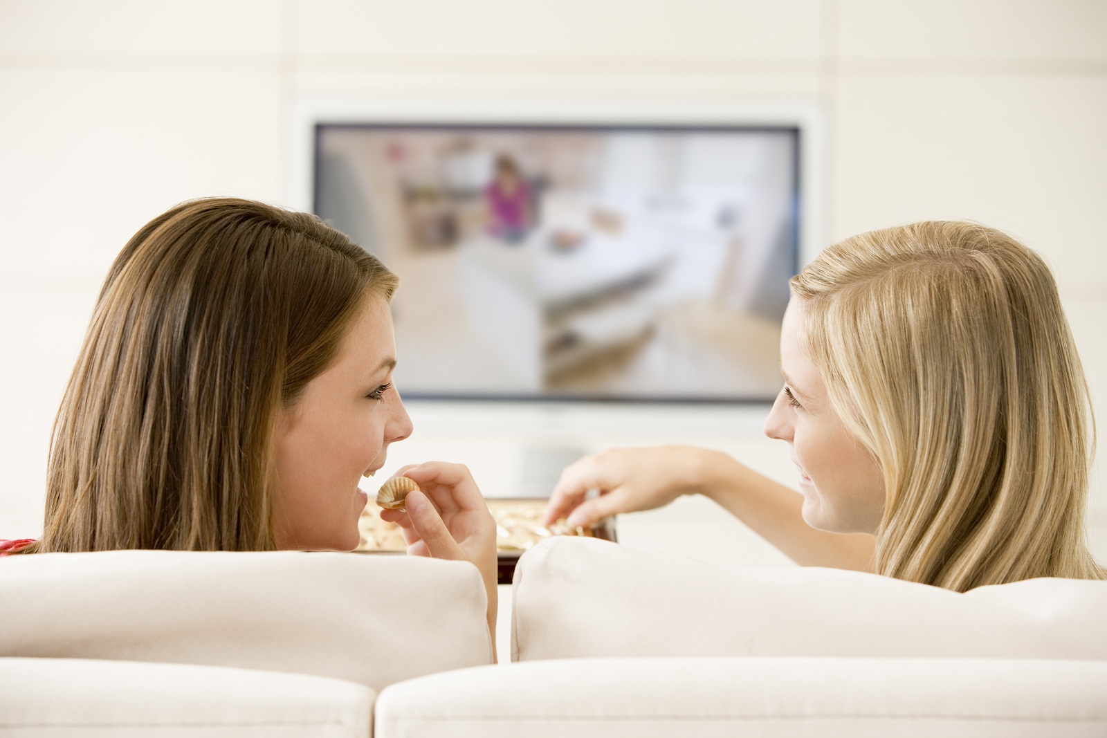 Teen girls relaxing at home on sofa watching tv