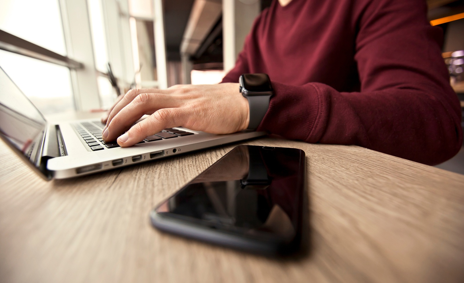 Vinnitsa, Ukraine - January 16, 2018: Photo of man working on Macbook at modern workplace with Apple watch on his hand and iphone 7 lying near the laptop