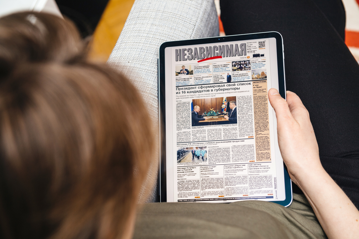 Paris, France - Apr 15, 2019: Woman reading on iPad Pro Apple News Plus Nezavisimaya Gazeta digital newspaper featuring breaking neabout 16 governors list made by Vladimir Putin Russian President