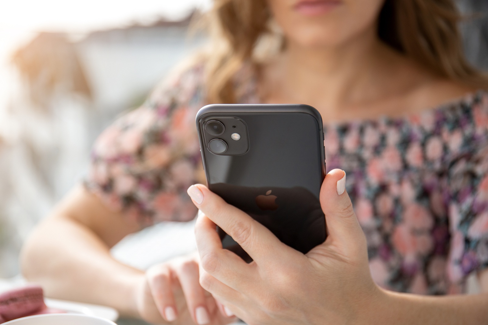 Anapa, Russia - October 4, 2019: Woman hand holding Apple iPhone 11 and sitting at the table. iPhone was created and developed by the Apple inc.