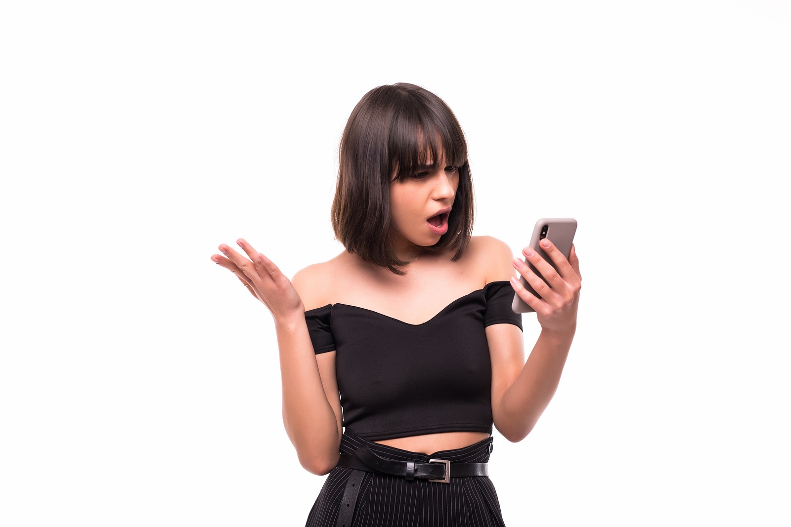 Annoyed angry young woman mad about spam message stuck phone looking at smartphone isolated on blank studio background, furious teen girl having problem with cellphone irritated by broken mobile