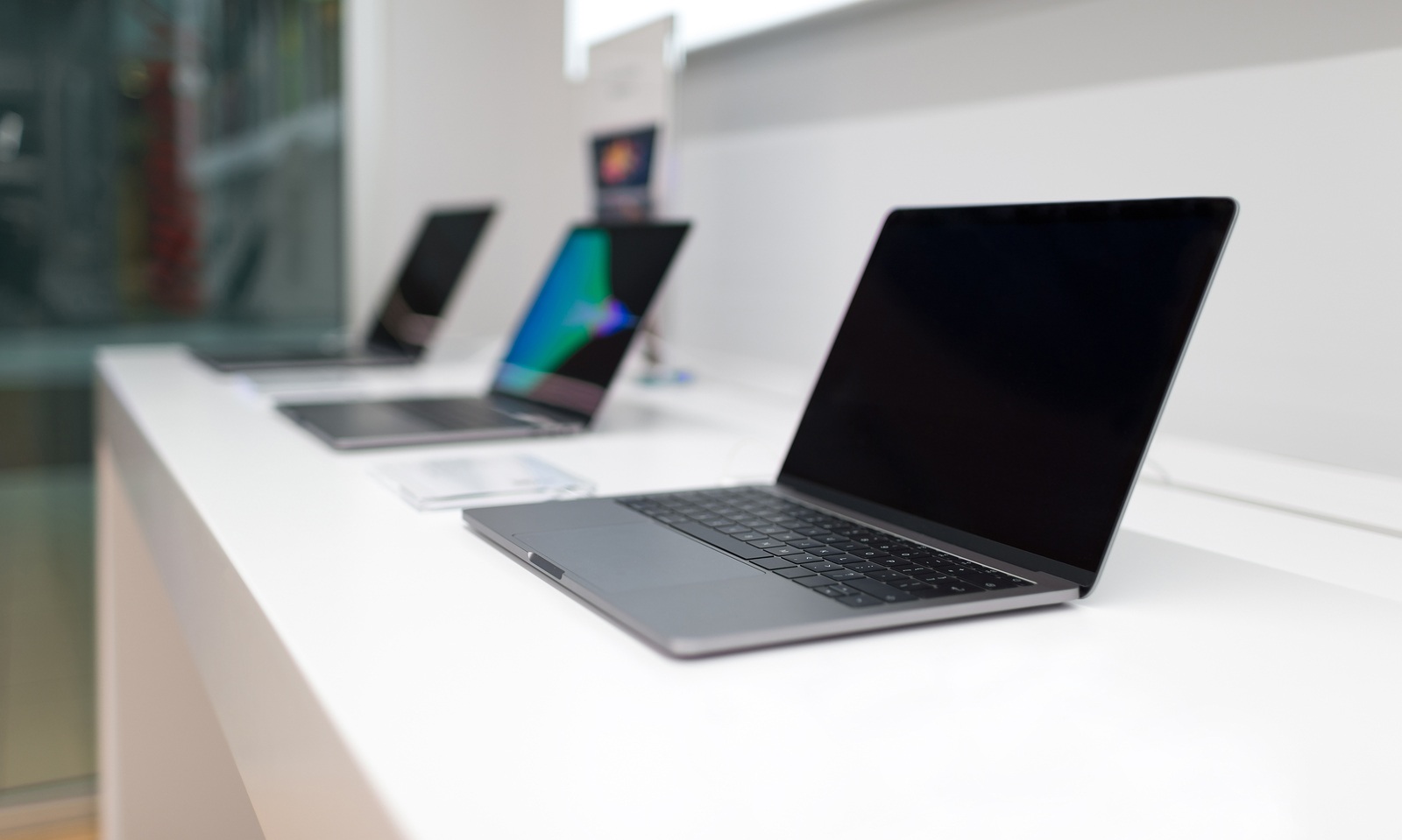 Belgrade, Serbia - March 21, 2018: New laptop with blank black screen on white table in electronic store. MacBook Pro with retina display, three in line.