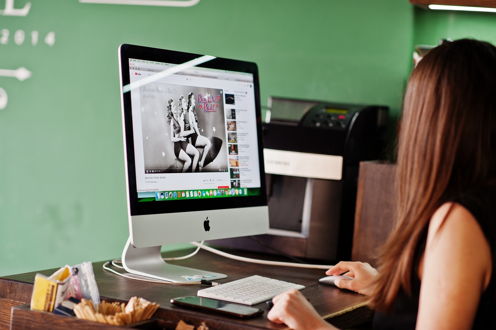 Kyiv, Ukraine - January 20, 2018: Girl sitting against Apple imac in office and watching You Tube music.