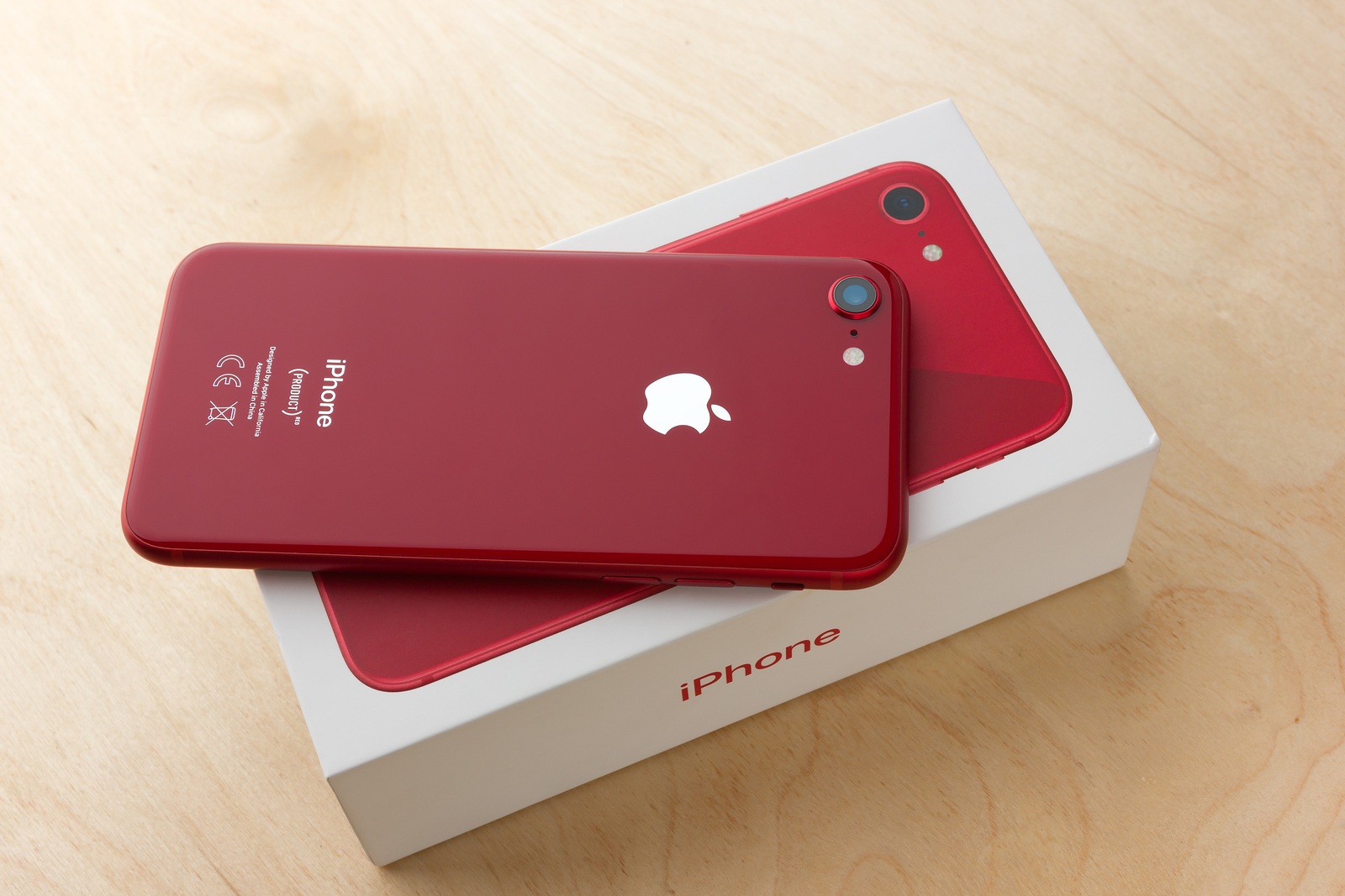 May 2018. Apple iPhone 8 (PRODUCT) RED and box lies on a wooden table. A new smartphone from the company APPLE close-up on a wooden surface.