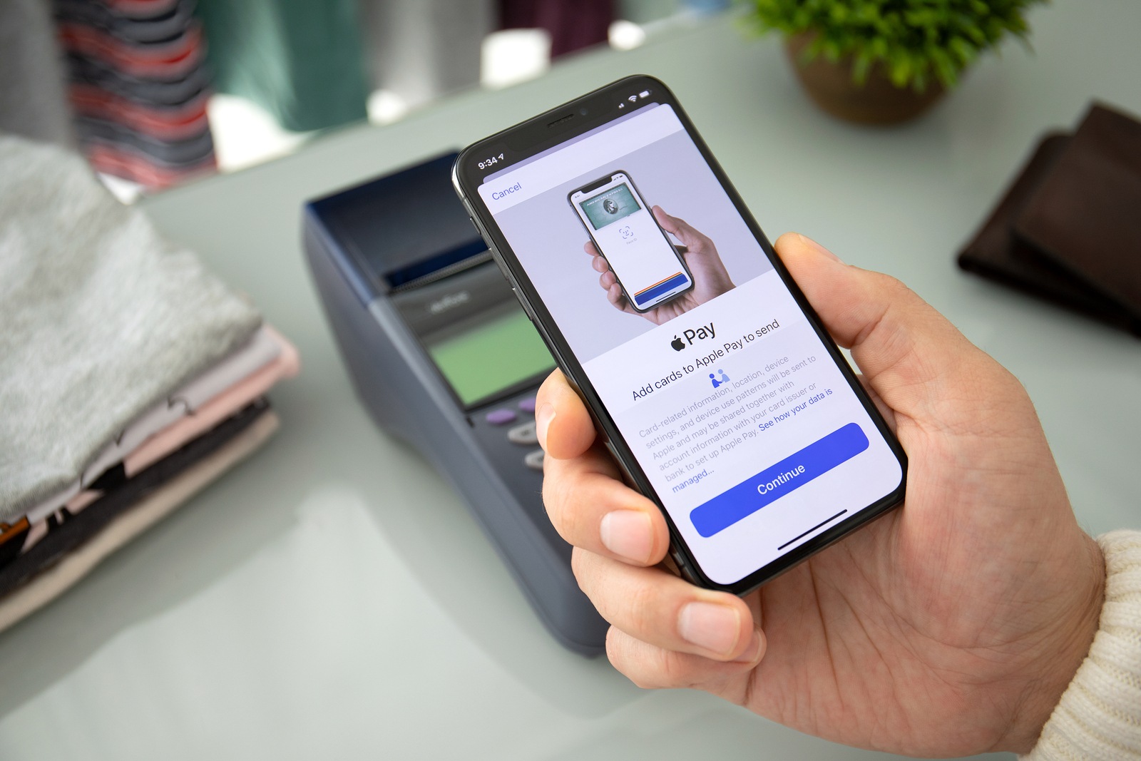 Anapa, Russia - August 12, 2019: Man hand holding iPhone X with Apple Pay on the screen and pay pass online terminal. iPhone was created and developed by the Apple inc.