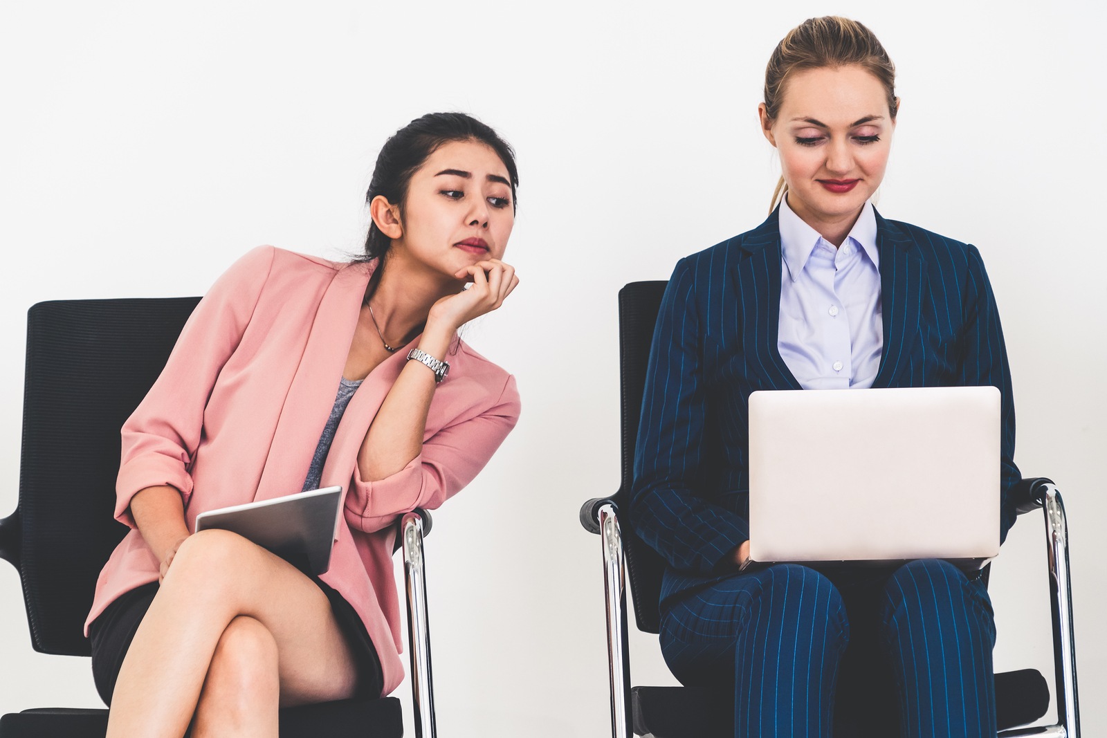 Curious businesswoman looking at the screen of laptop computer of another businesswoman spying stealing idea and copying private information from coworker at workplace. Plagiarism concept.