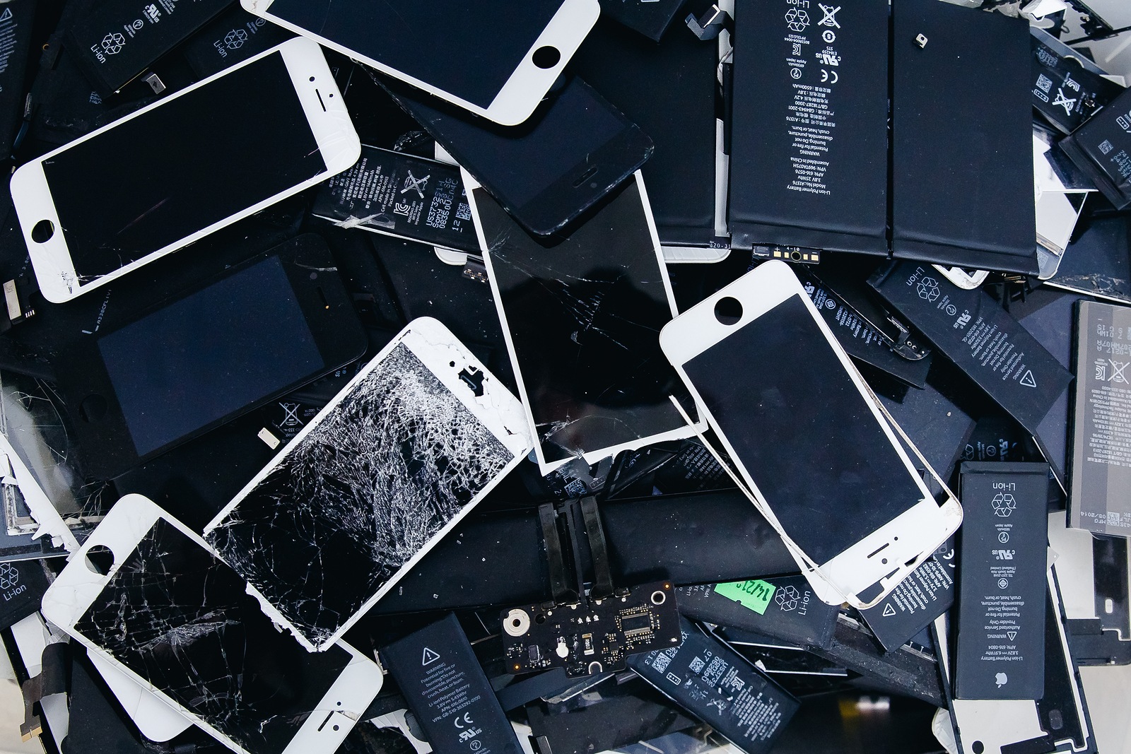 TOMSK, RUSSIA - June 29, 2017: Close-up of used mobile phone batteries, tablets, broken screens LCD iPhone, panels, laptop batteries collected for disposal in plastic packaging in the repair room and greenpeace.