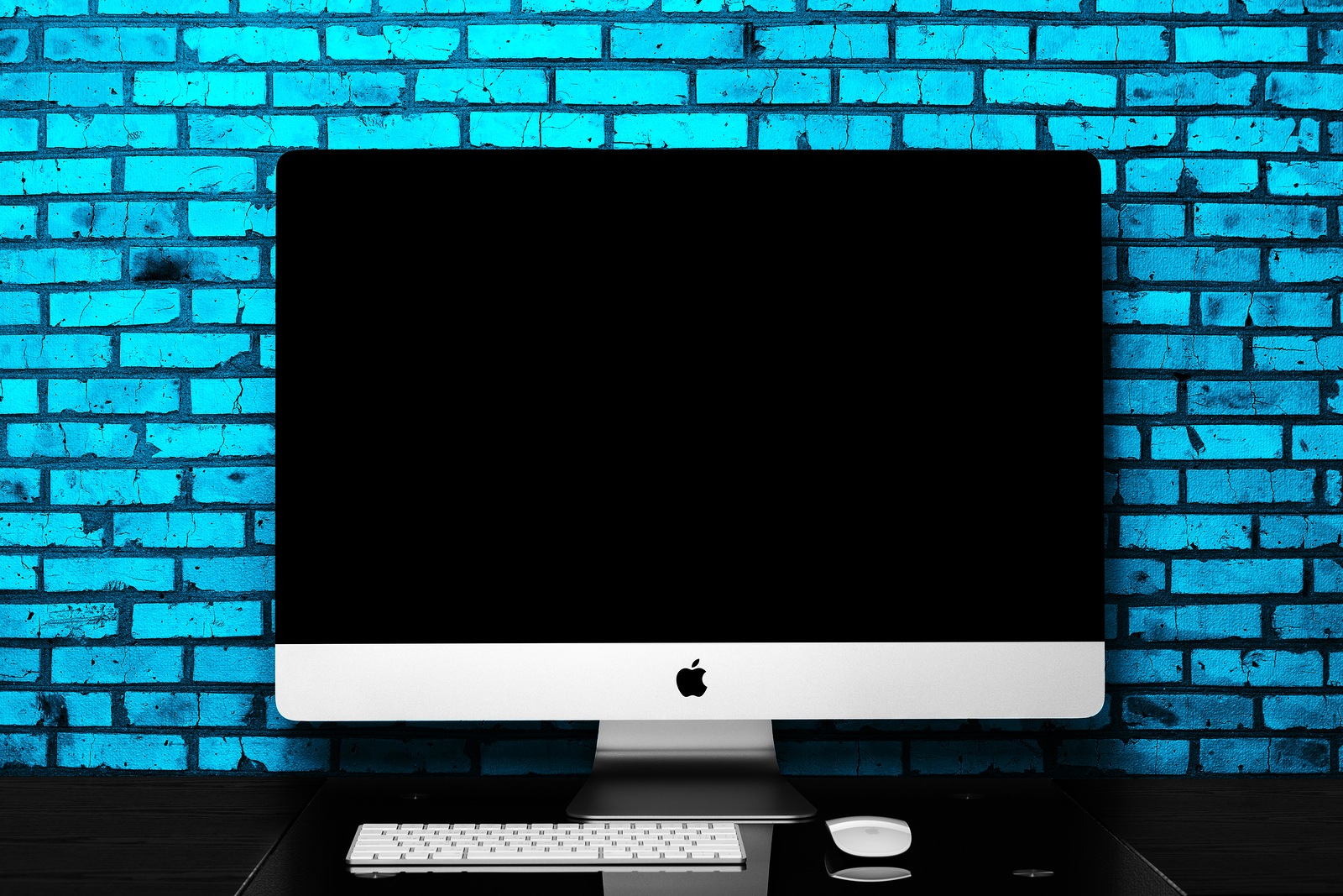 UKRAINE, RIVNE, June 15, 2018. Apple Computer iMac 27 retina display 5K keyboard and magic mouse on black table. Isolated on a blue background