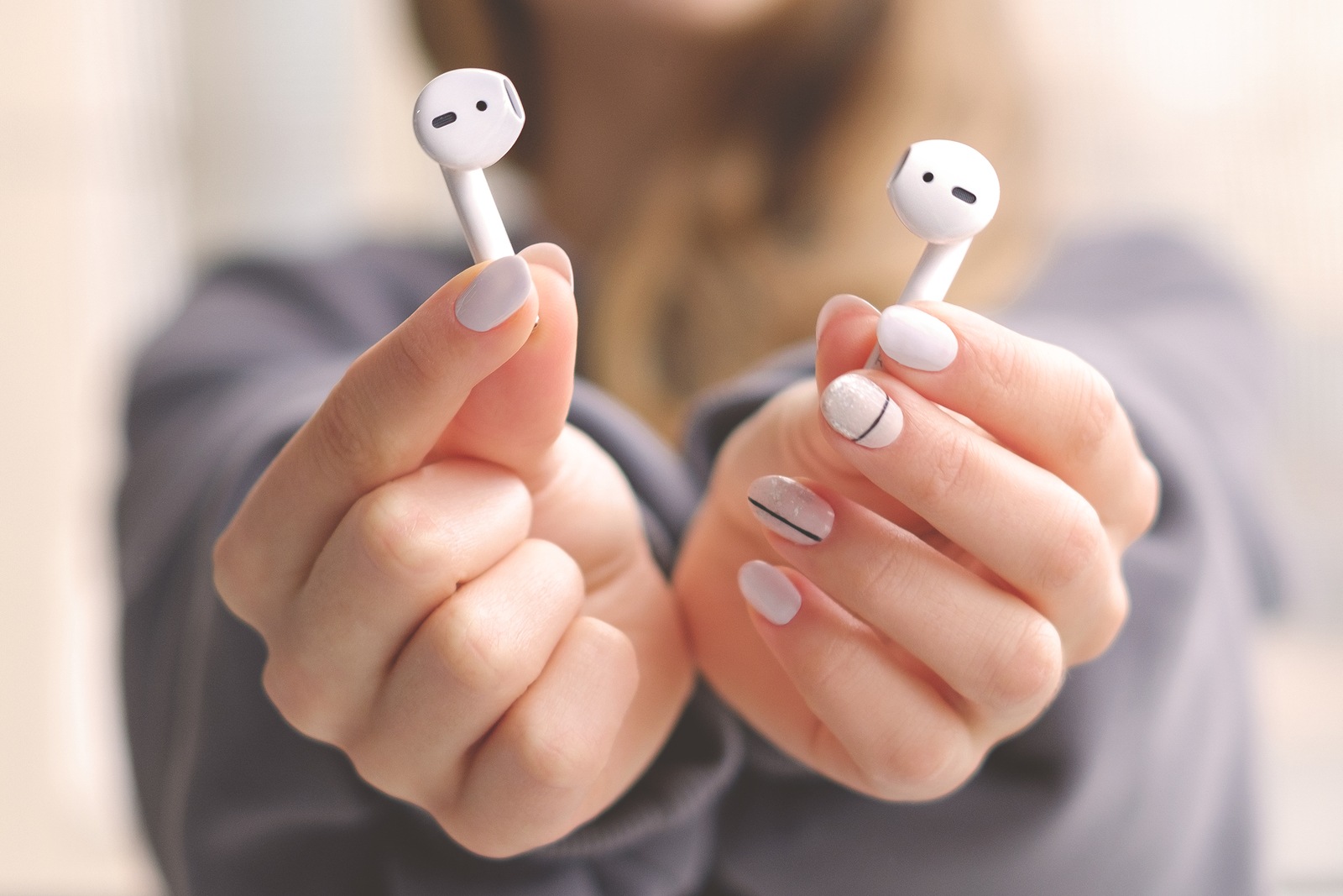 White wireless airpods in female hands. Modern mobile technology.