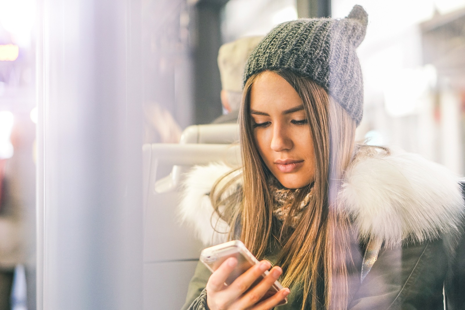 Young woman using her smart phone while sitting in a bus - Pretty girl connecting on her social network with her mobile phone - Concept of youth people addiction to new technology