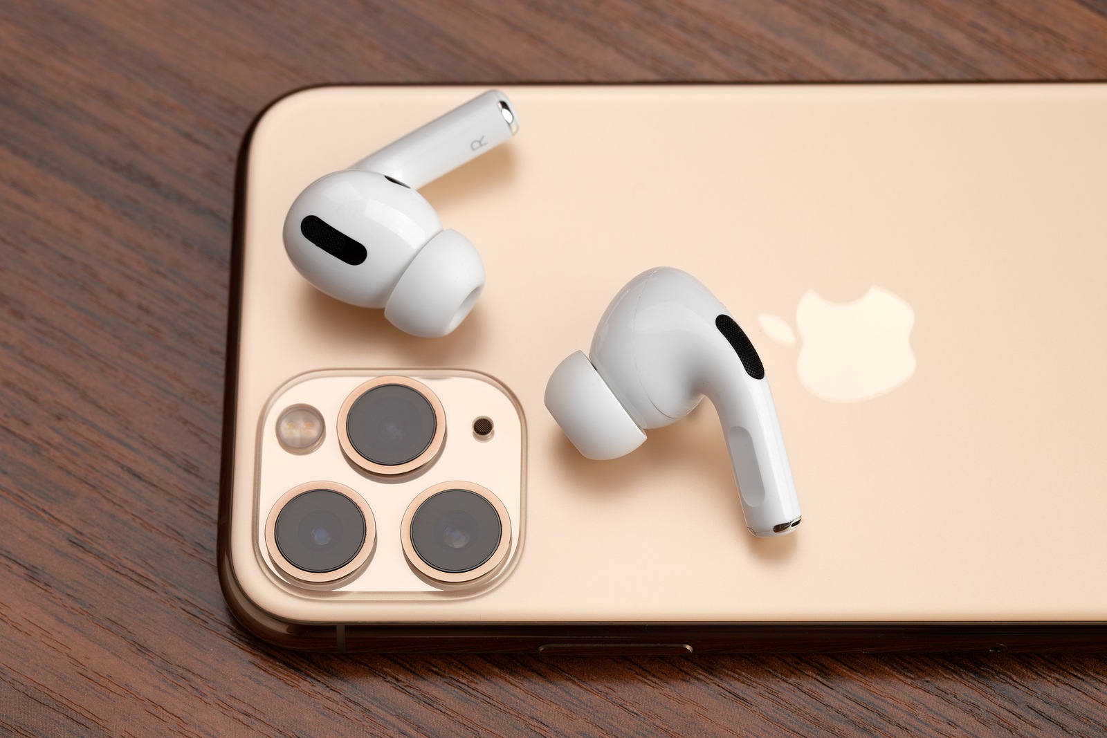 Rostov-on-Don, Russia - December 2019. Apple AirPods Pro and iPhone 11 Pro on a wooden table. Wireless headphones and smartphone close-up.