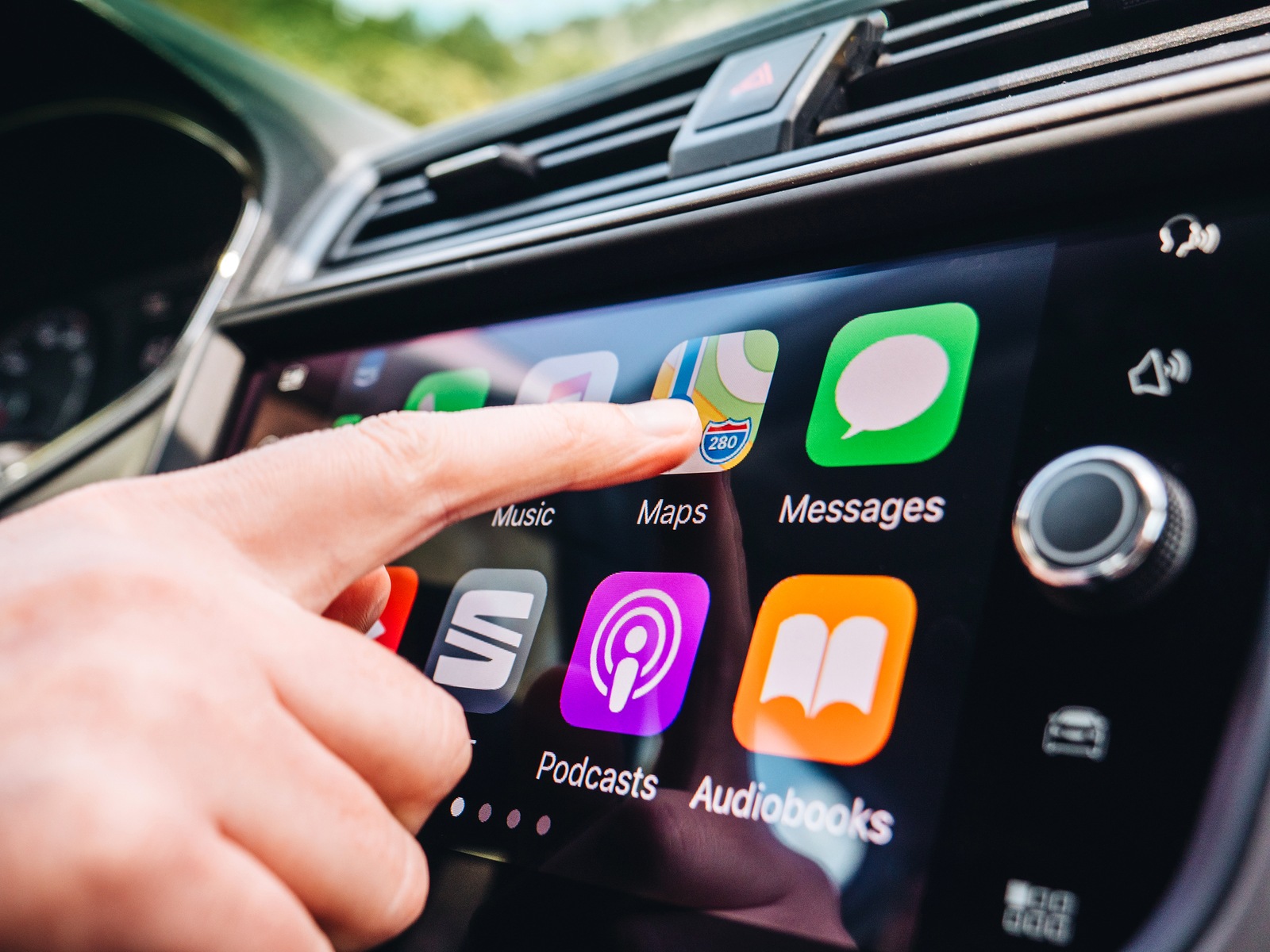 PALMA DE MALLORCA, SPAIN - MAY 10, 2018: Woman pressing Apple Maps button on the Apple CarPlay main screen in modern car dashboard during driving on Spanish holiday highway