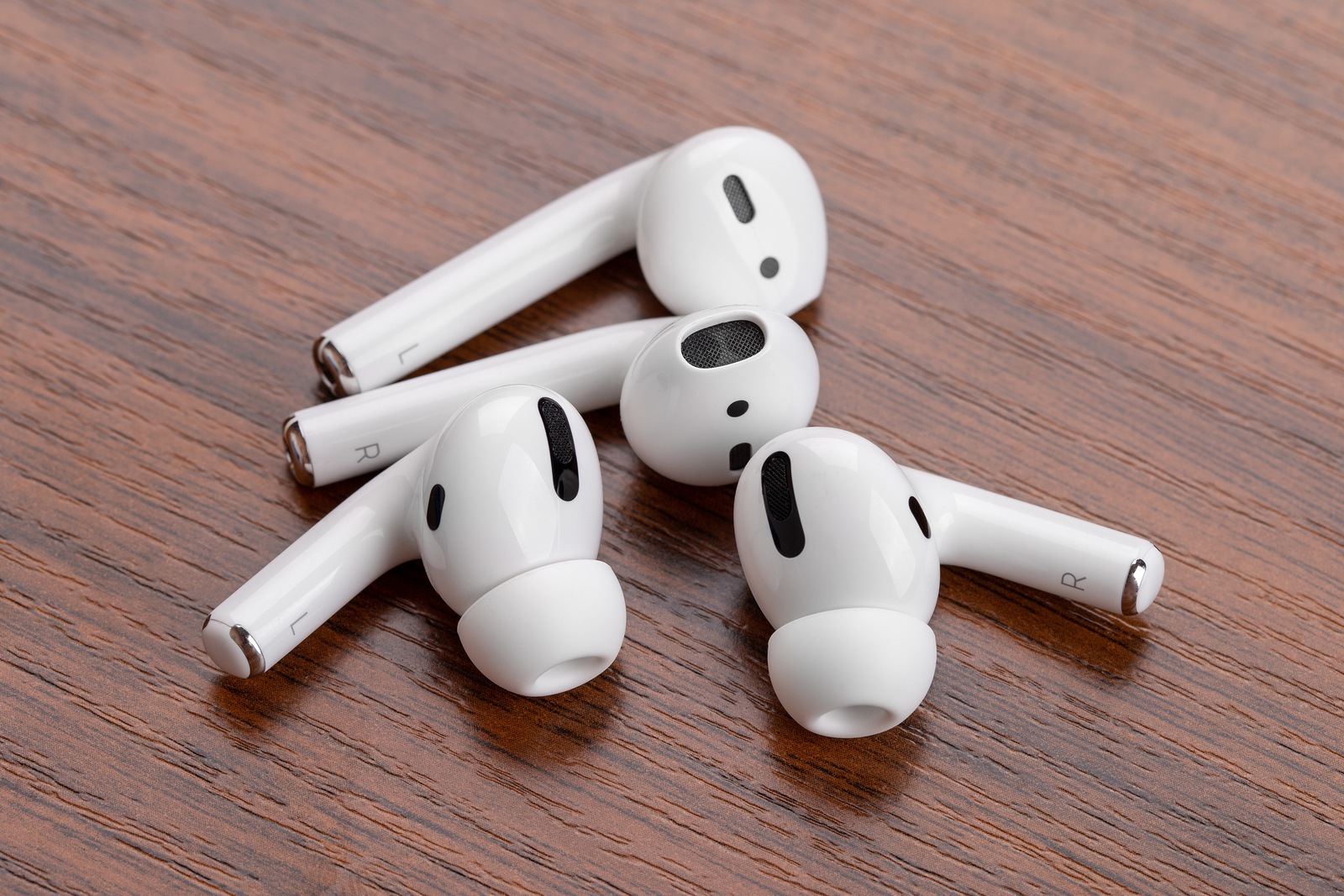 Rostov-on-Don, Russia - December 2019. Apple AirPods Pro and AirPods on a wooden table. Wireless headphones close-up.