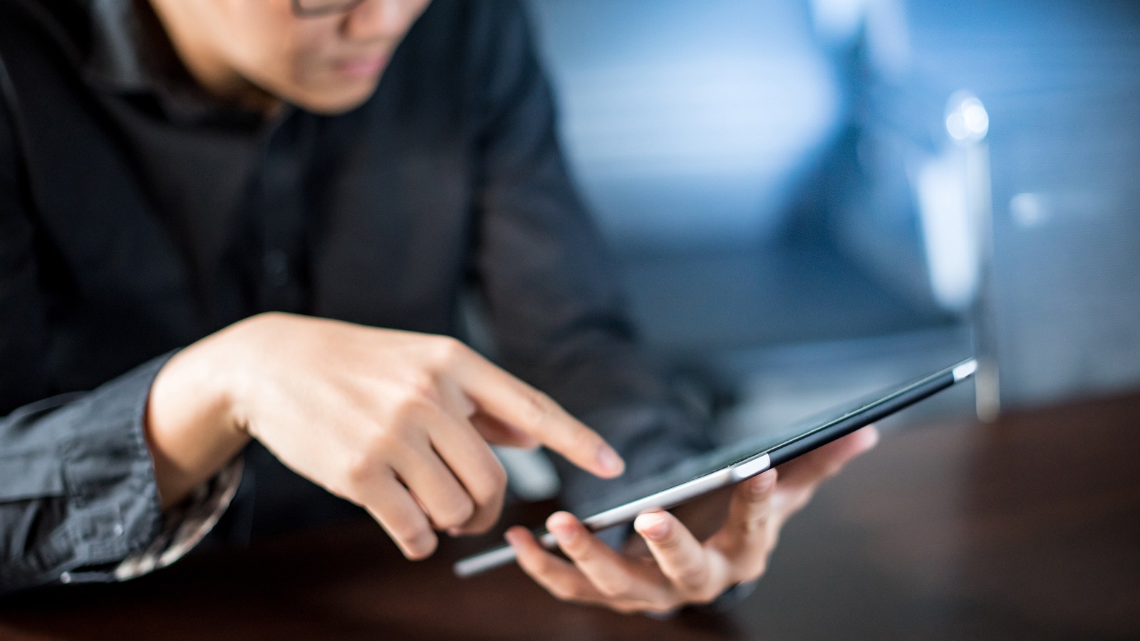 Young Asian businessman using digital tablet in office meeting room. Male entrepreneur reading news on social media app. Online marketing and Big data technology for E-commerce business.