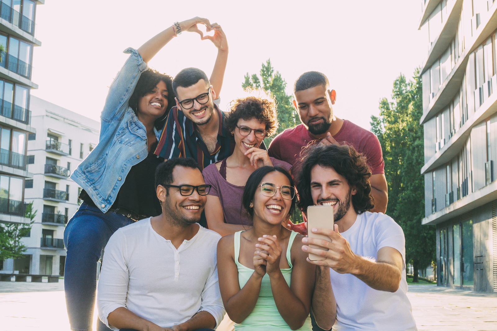 Excited overjoyed multiethnic people taking group selfie outside. Mix raced team of friends posing and laughing at phone camera. Group selfie concept