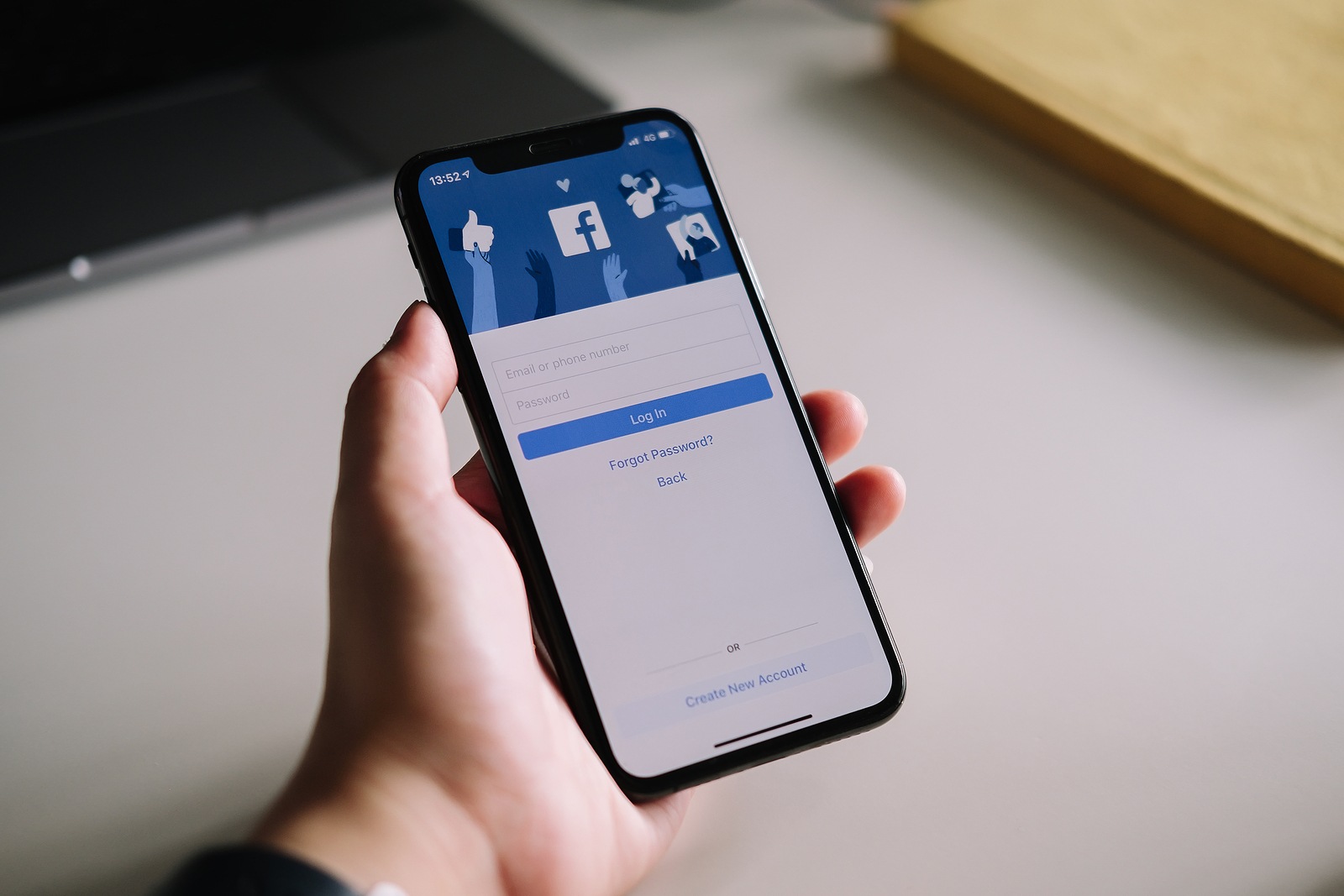 CHIANG MAI , THAILAND - JULY 3, 2020 : Woman hand holding iPhone X to use facebook with login screen.Facebook is a largest social network and most popular social networking site in the world