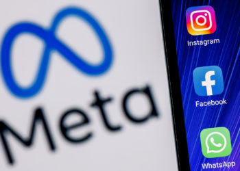 Kazan, Russia - Oct 28, 2021: Facebook changes its name to Meta. Smartphone with Facebook, Whatsapp and Instagram app icon on the background of Meta logo.